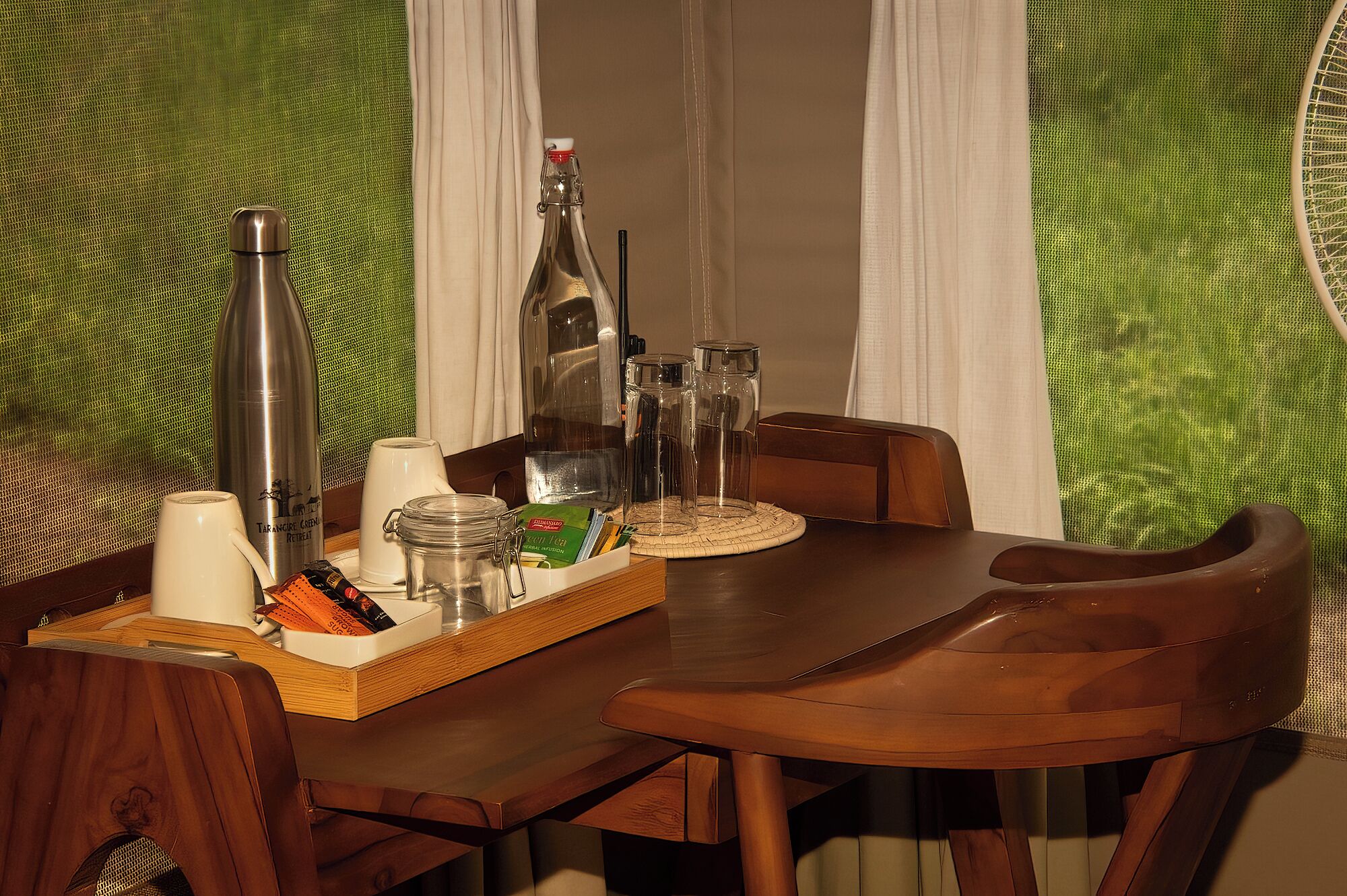 Une table à manger avec un plateau contenant divers objets, une bouteille et des verres.
