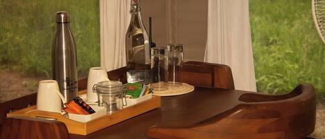 Une table à manger avec un plateau contenant divers objets, une bouteille et des verres.