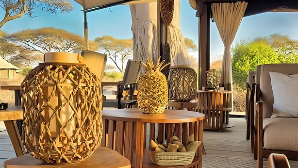 Un área de estar al aire libre con toldo, muebles de madera, elementos decorativos tejidos y vistas al paisaje.