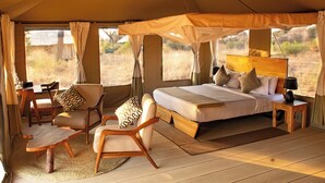 Una habitación con carpa, una cama, dos sillas, una mesa y una mesita de noche.