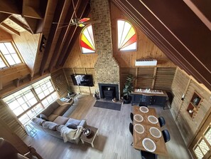 A spacious loft-style living area with a fireplace, a television mounted on the wall, and a dining table with chairs.