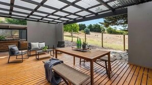 Une terrasse extérieure avec une plateforme en bois, des sièges et une table.
