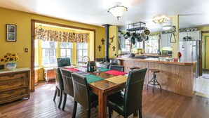 A kitchen with wooden flooring, a dining table with chairs, a bar area, and a refrigerator. - 'Wagon Wheel Hideaway' Near Fishing in Creede! (South Fork)