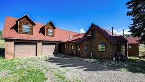 A two-story wooden house with a red roof, a front porch, and a gravel driveway. - 'Wagon Wheel Hideaway' Near Fishing in Creede! (South Fork)