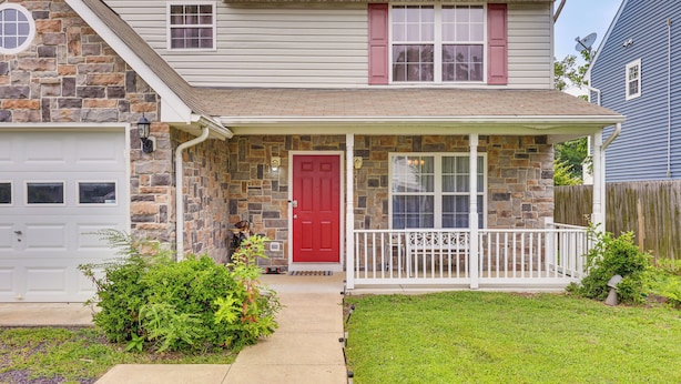 A two-story house with a stone facade, a red front door, and a covered porch with a white railing. - 1 Mi to Colonial Beach Boardwalk! Cozy Family Home (Colonial Beach)