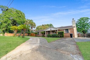 A residential house with a front yard, a driveway, and a brick exterior.