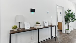 A modern hallway with a wooden console table displaying welcome signs, a small plant, and a lamp. - Heart of Cedartown | 0.3 miles from the Silver Comet Trail (Cedartown)