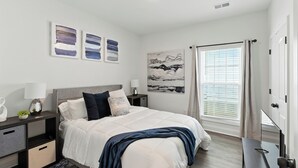 A modern bedroom with a large bed, bedside tables, a nightstand, a desk, and a window with curtains. - Heart of Cedartown | 0.3 miles from the Silver Comet Trail (Cedartown)