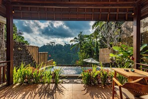 A wooden deck with a view of a natural landscape, a small pool, and tropical plants. - Belas Vana Villa Ubud by Dhananjaya Hospitality (Sebatu)