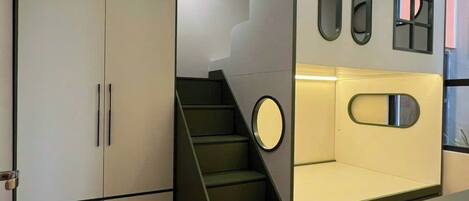 Une chambre moderne dotée d’un escalier intégré, d’une armoire et d’un coin salon agrémenté de miroirs.
