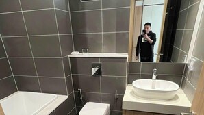 A modern bathroom with a toilet, sink, and bathtub. - Oanh Luxstay (Bac Hong Linh)