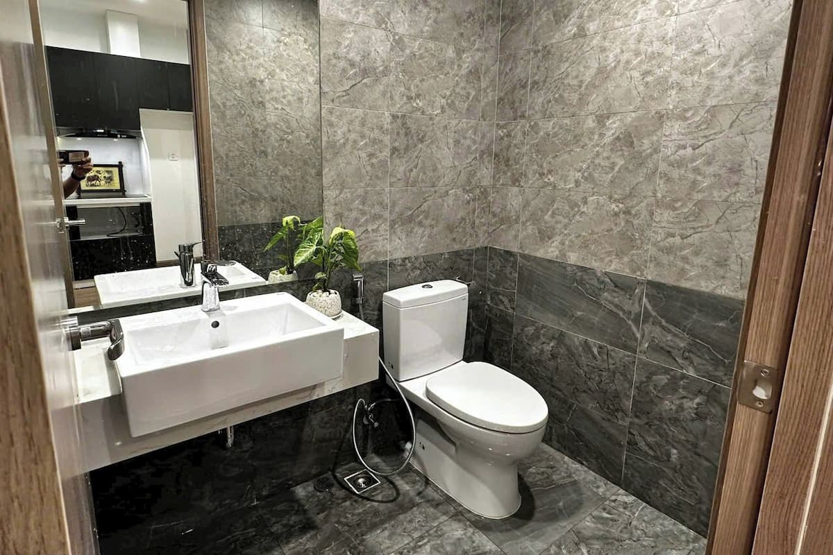 A modern bathroom with a white sink, toilet, and marble walls.