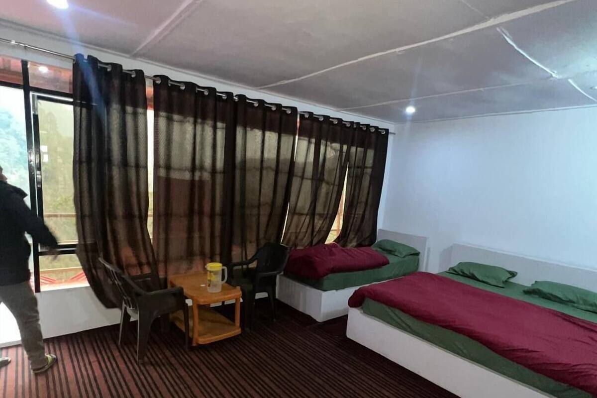 Una habitación con cama, escritorio, silla y ventana con cortinas.