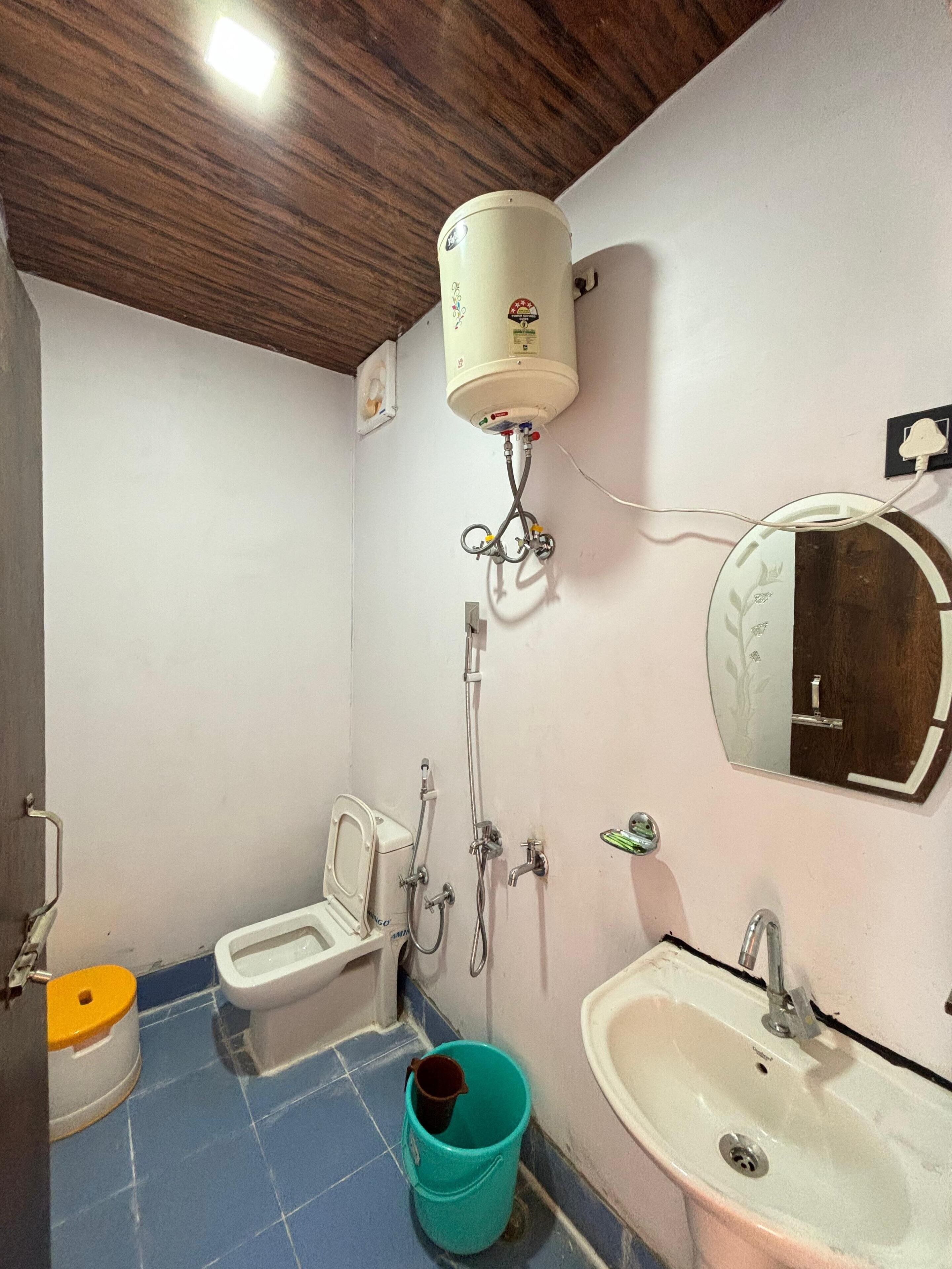 A bathroom with a toilet, bidet, sink, and a water heater mounted on the wall.