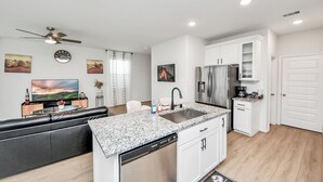 Una cocina moderna con gabinetes blancos, un refrigerador de acero inoxidable y un lavavajillas integrado.
