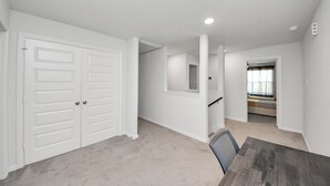 Una habitación amplia con un armario grande, una mesa de comedor y una escalera que conduce a otro nivel.