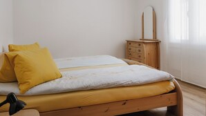 Ein Schlafzimmer mit einem hölzernen Bett, einem Nachttisch mit Spiegel und einer Lampe.