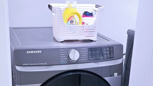 A Samsung washing machine with a basket of laundry on top.