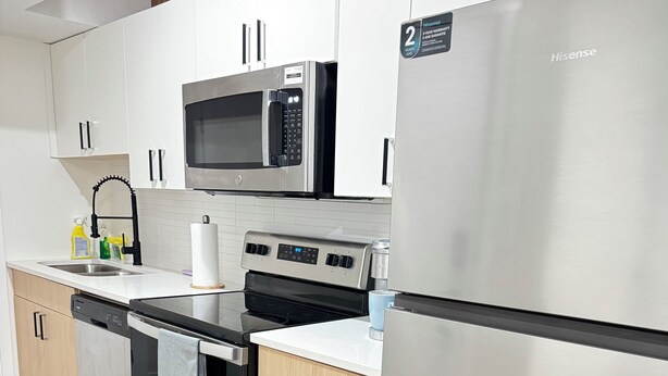 A modern kitchen with stainless steel appliances, a microwave, oven, and a refrigerator.