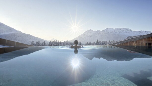 A person in a clear pool with a mountain backdrop. - Apartment Near Glacier ski Area (Kaprun)