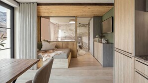 A modern kitchen with wooden cabinets, a dining area with a wooden table and chairs, and a cozy seating area with a sofa and cushions. - Apartment Near Glacier ski Area (Kaprun)