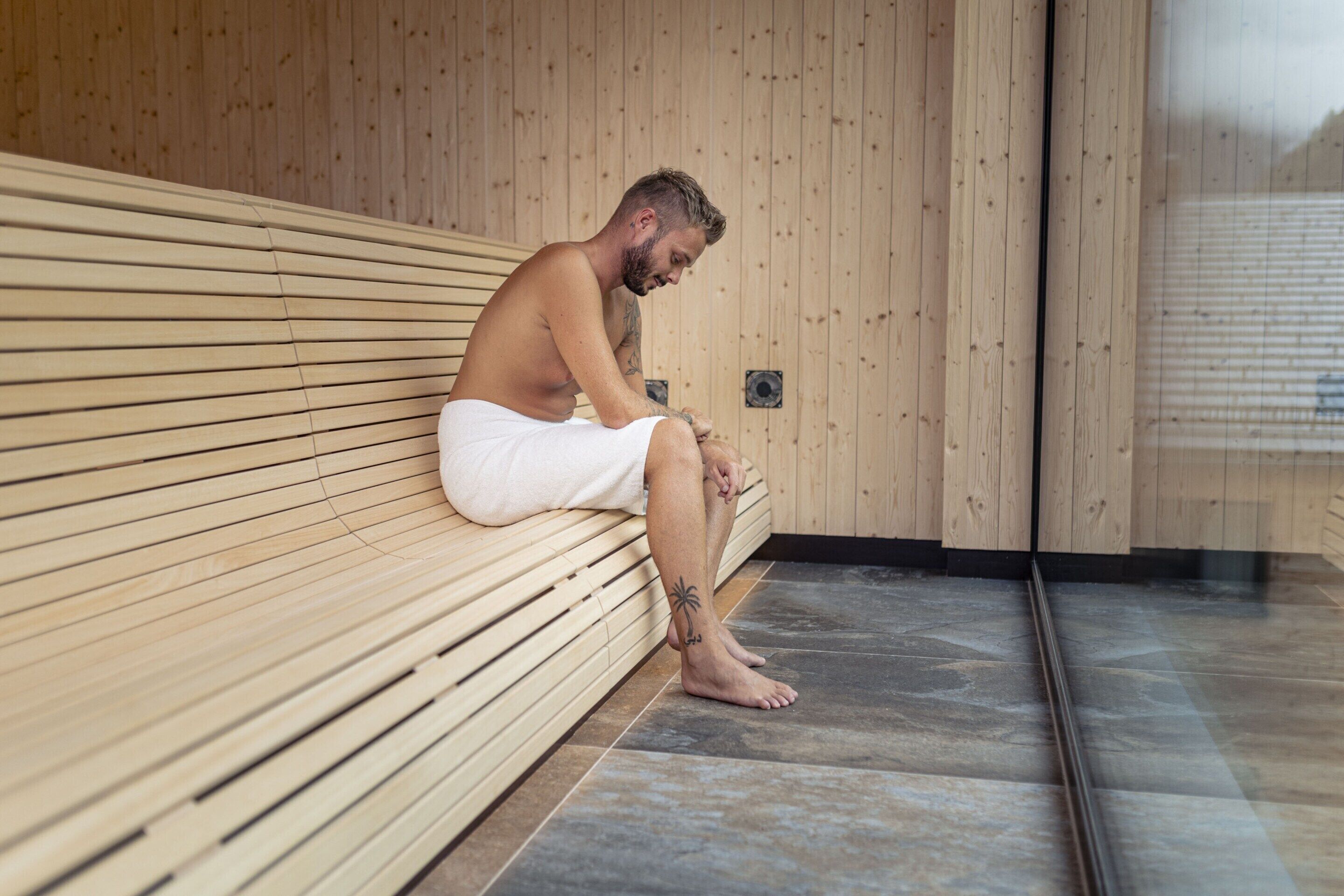 A wooden bench in a sauna room with a tiled floor.