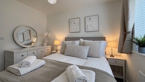 Ein ordentlich eingerichtetes Schlafzimmer mit Bett, Nachttischen, einem Spiegel und Bildern an der Wand.