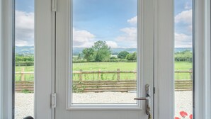 A door with a view of a rural landscape, including a fence and trees. - Modern Snitton Cottage & Gardens (Snitton)