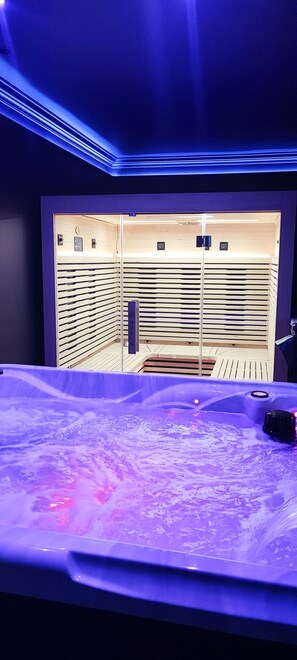 Un cuarto de spa con una camilla de masaje, un banco de madera y una silla de masaje fijada a la pared.