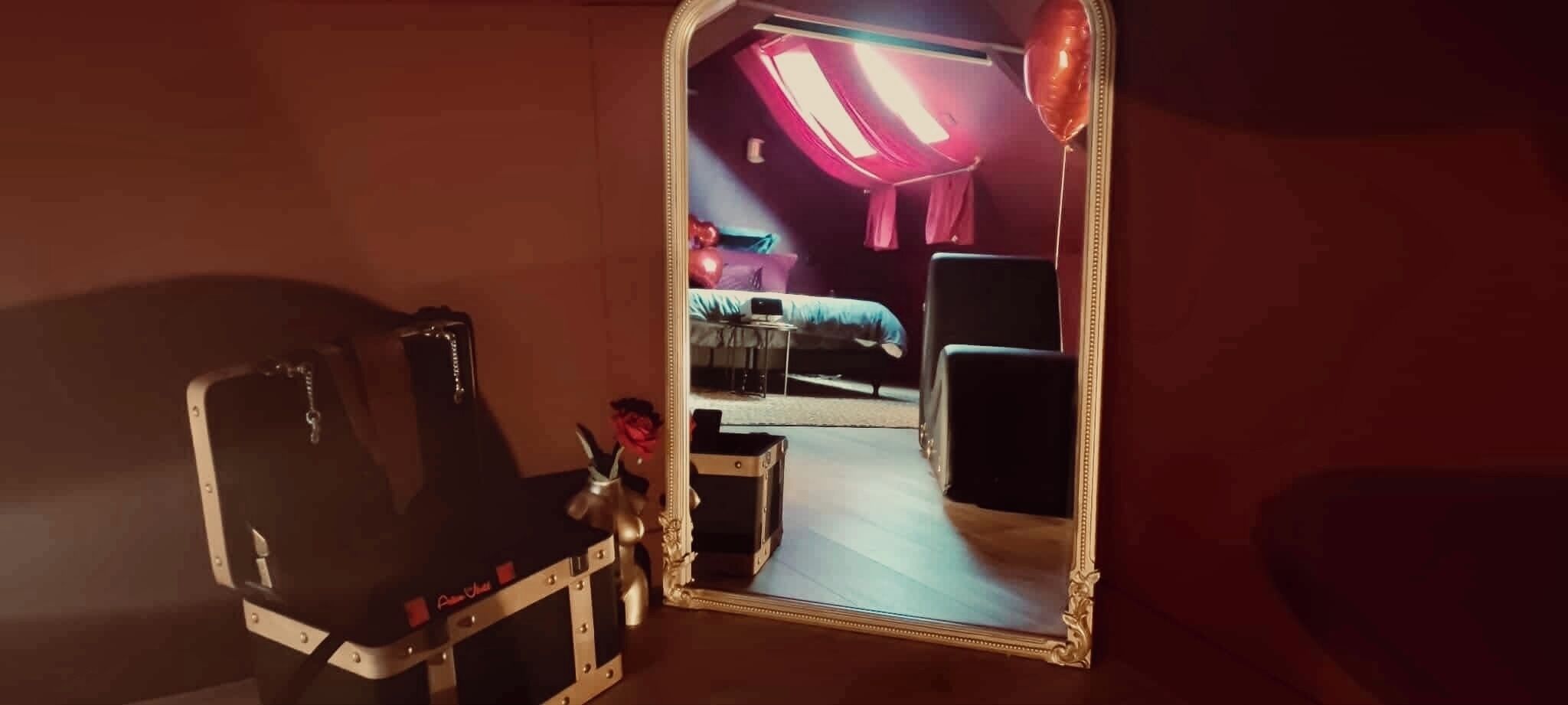 Una habitación con una cama, un aparador, un espejo y una pequeña estatua.