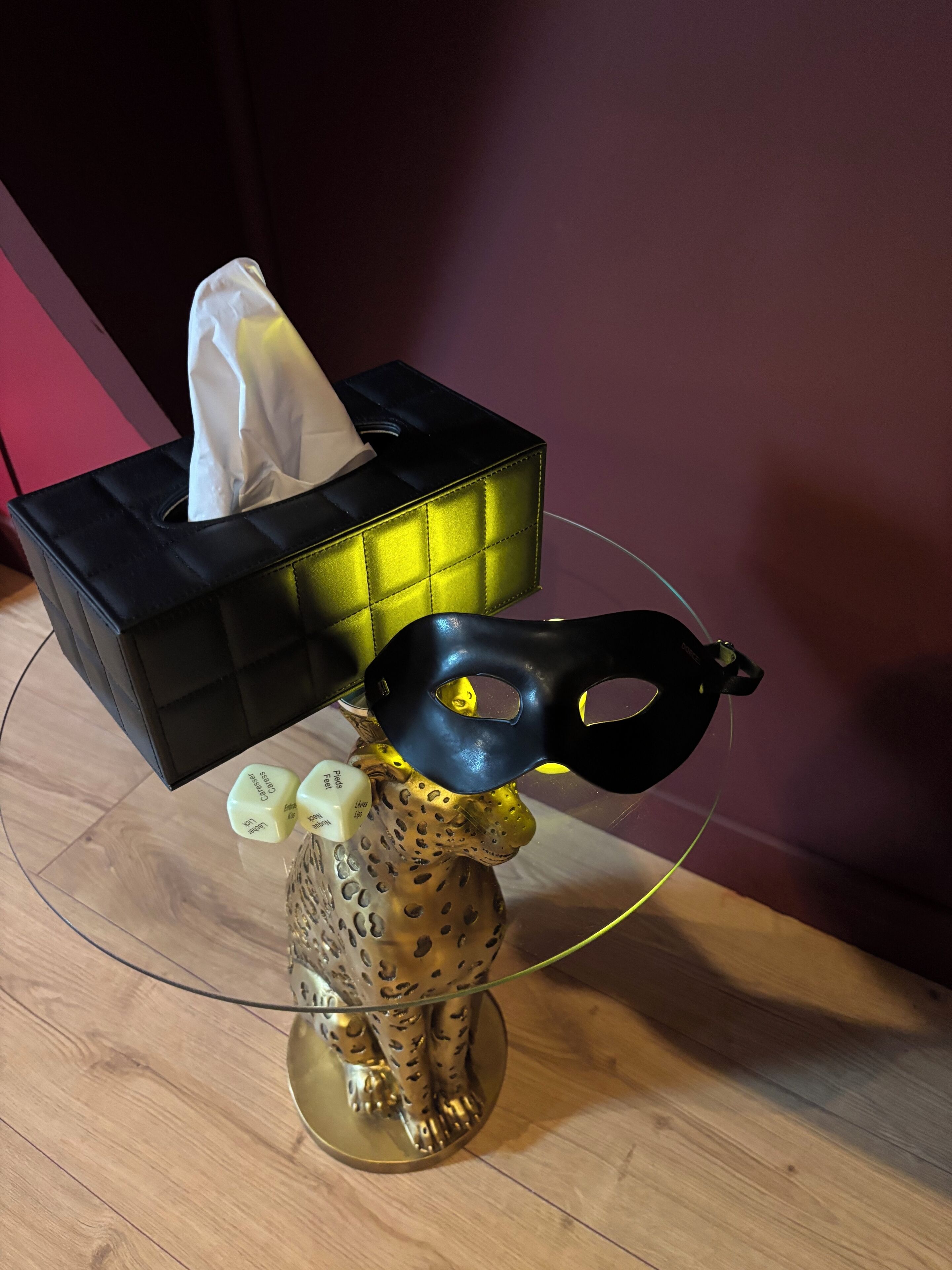 A tissue box on a table with a decorative item featuring a mask and dice.