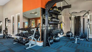 Ett gym med olika typer av träningsutrustning, inklusive hantlar, kettlebells och en knäböjsställning.