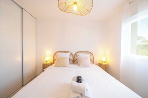 Une chambre Ă coucher avec un lit, des lampes de chevet, un luminaire suspendu et une fenĂȘtre.