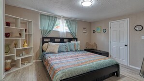 Une chambre à coucher comprenant un lit, une table de chevet, une étagère et une porte.