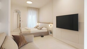 A modern bedroom with a bed, a TV mounted on the wall, and a large window with curtains. - Piano 7 | Bright penthouse with terrace (Torino)