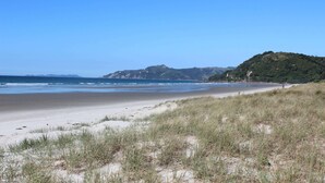 A beach with sand dunes and a clear view of the ocean. - 5 minutes walk to beautiful beach & shops, fully fenced section pet friendly. (Matarangi)