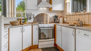 Een moderne keuken met witte kasten, een roestvrijstalen afzuigkap en een inbouwoven.