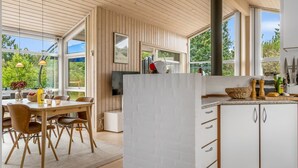 Een moderne keuken met houten kastjes, een groot raam en een eethoek met een tafel en stoelen.