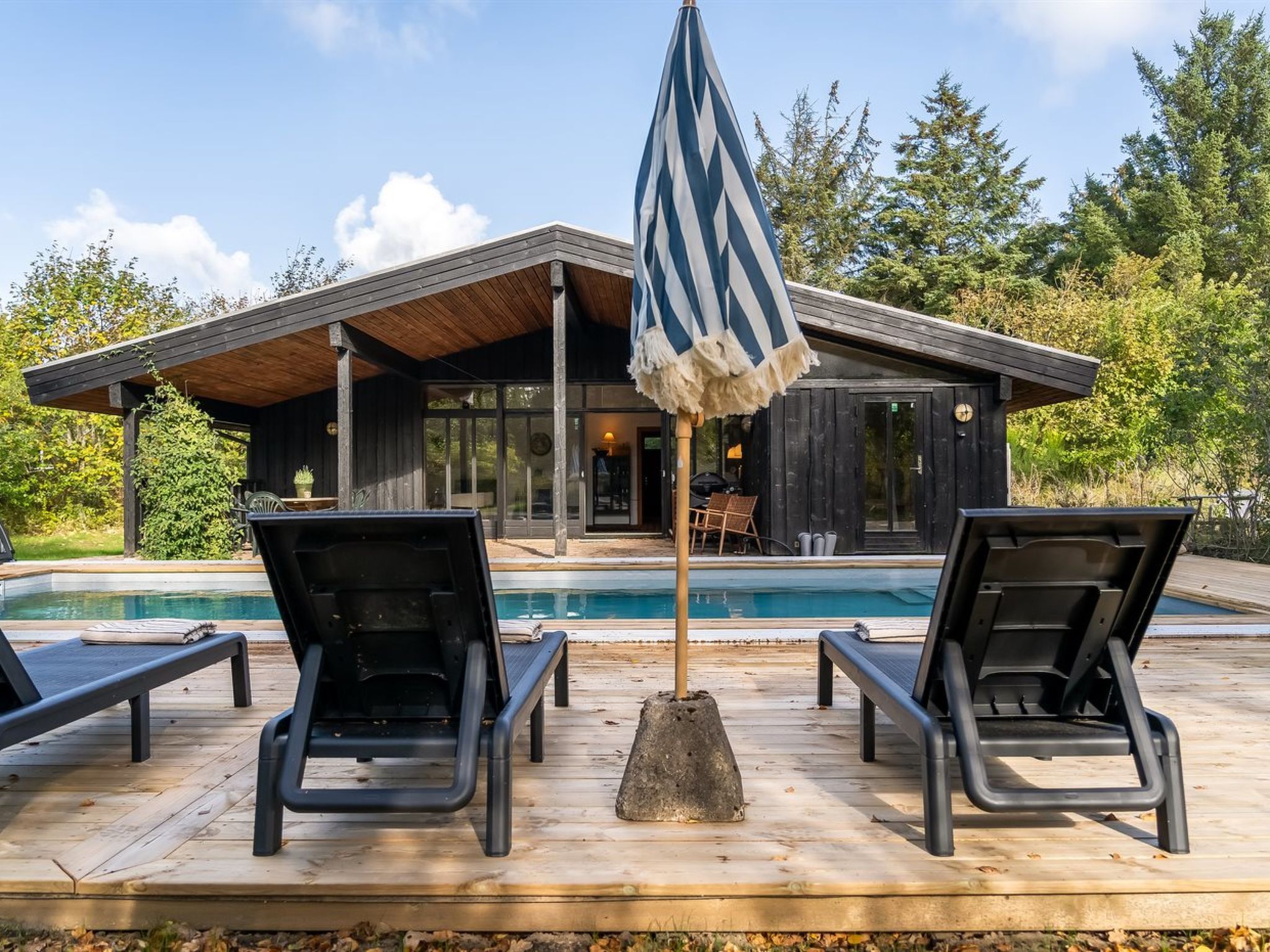 Een zwembadgedeelte met ligbedden en een houten terras.