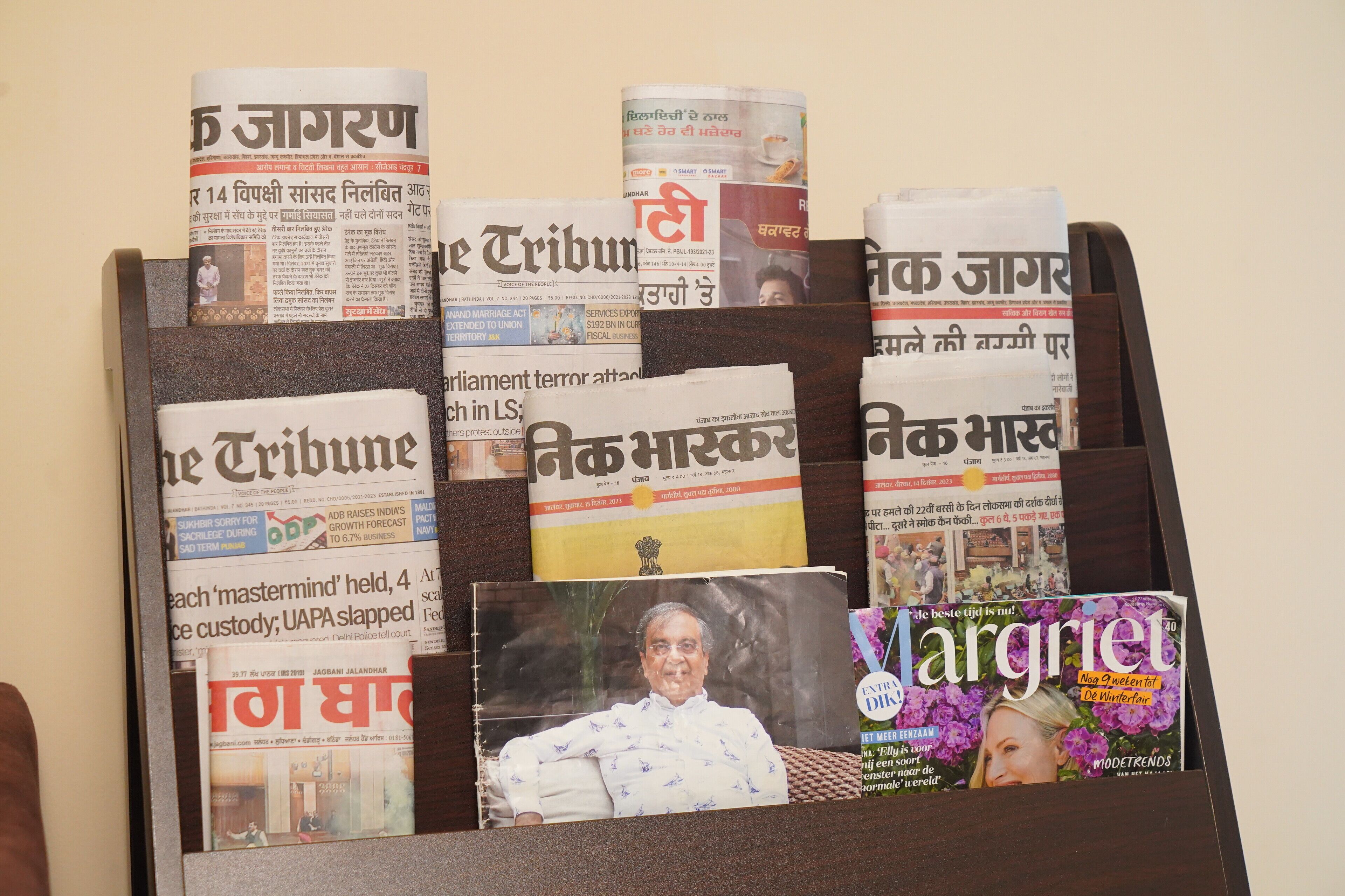 A magazine rack with various newspapers and a magazine.