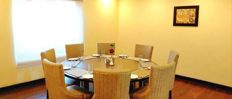 A conference room with a round table, six chairs, and a vase with a flower.