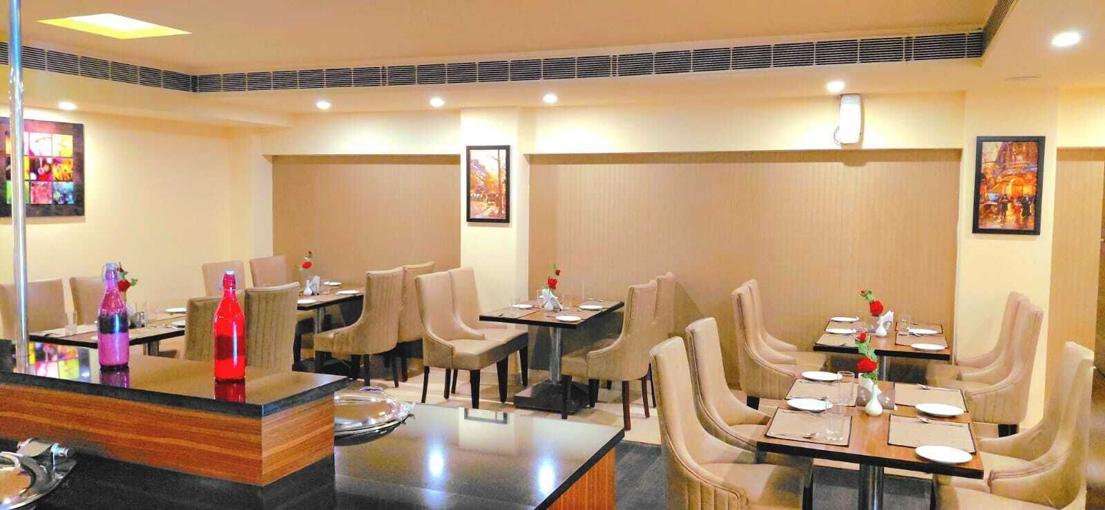 A restaurant with multiple tables and chairs, each set with plates, glasses, and cutlery.