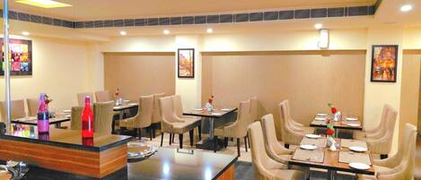A restaurant with multiple tables and chairs, each set with plates, glasses, and cutlery.