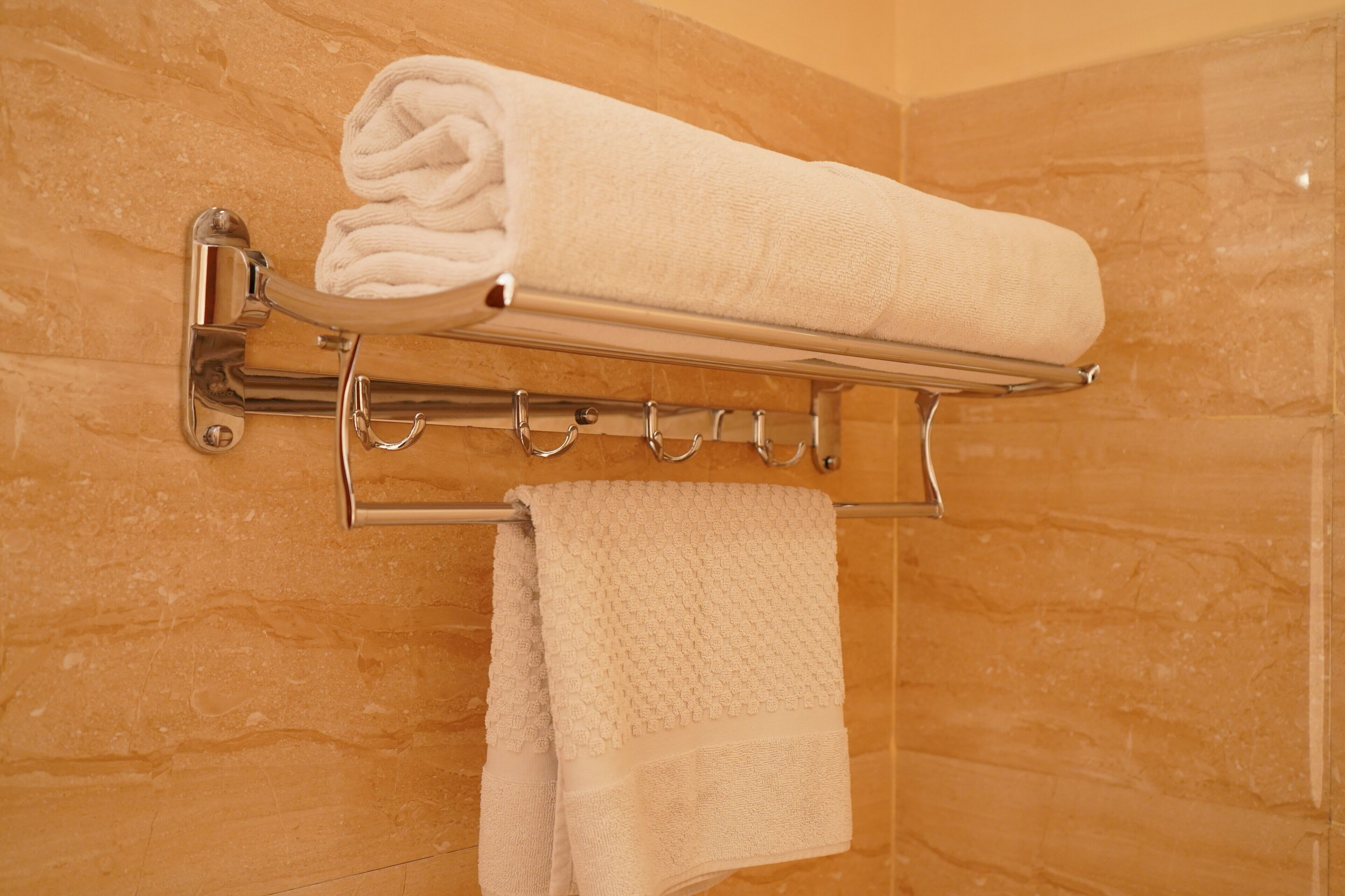 A bathroom with a towel rack holding a neatly folded towel and a rolled towel.