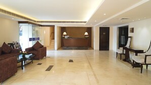 Eine Hotelhalle mit einer Rezeption, zwei Sofas, einem Couchtisch und einem Essbereich.