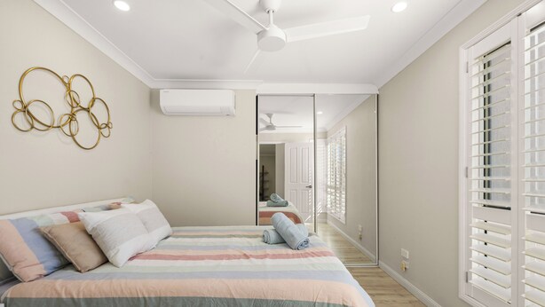 Un dormitorio con una cama grande, un ventilador de techo y una ventana con persianas.