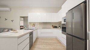 Una cocina moderna con gabinetes blancos, un refrigerador de acero inoxidable y piso de madera.