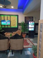 A living room with a sofa, chairs, a coffee table, a TV, and a ceiling fan.