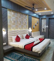 A modern bedroom with a large bed, two bedside tables, a ceiling fan, and a decorative wall panel.