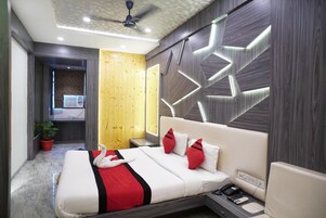 A modern hotel room with a large bed, a ceiling fan, and a wall-mounted air conditioning unit.